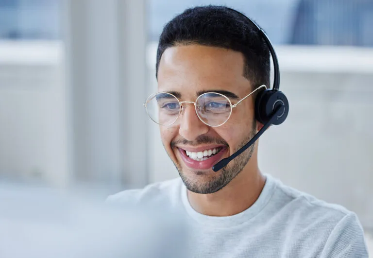 Person with glasses sat at a desk wearing a headset.