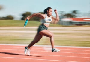 Person running on track with baton in their hand.