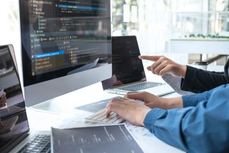 People sat together brainstorming and coding on computer.