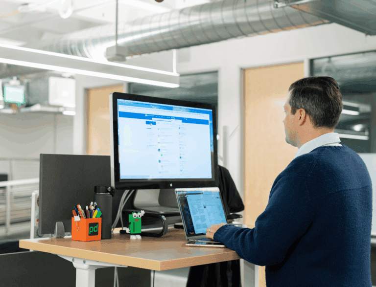 Business person stood at standing desk scrolling on LinkedIn.